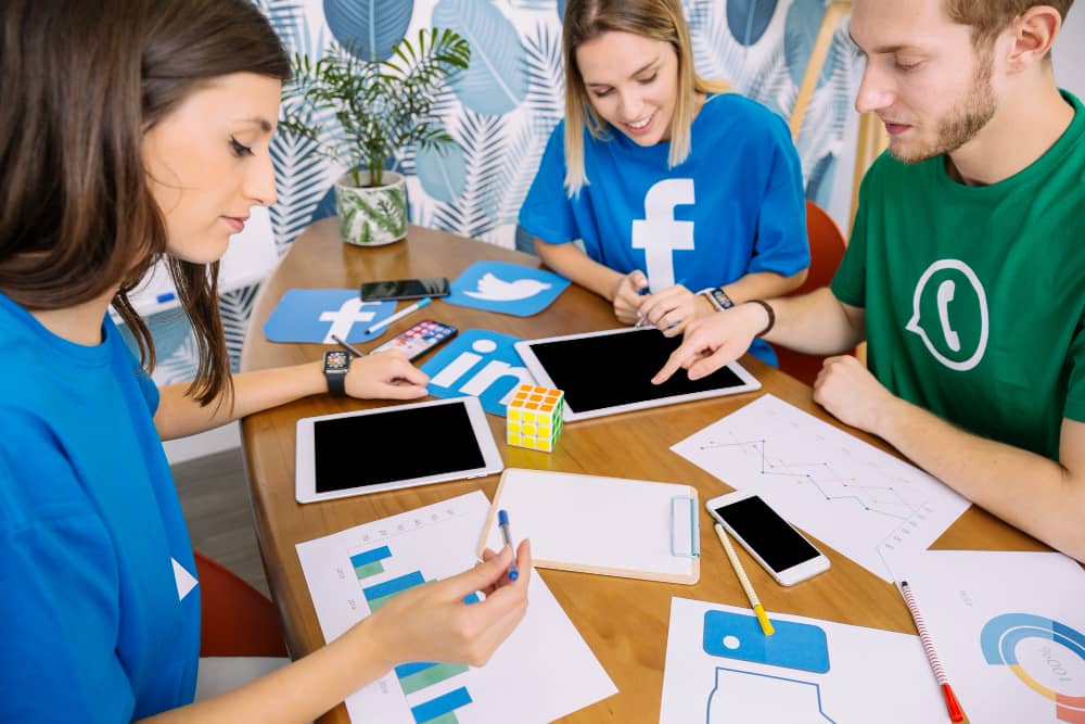 Team of digital marketers analyzing social media growth using Facebook, LinkedIn, WhatsApp, and Twitter for business strategy.